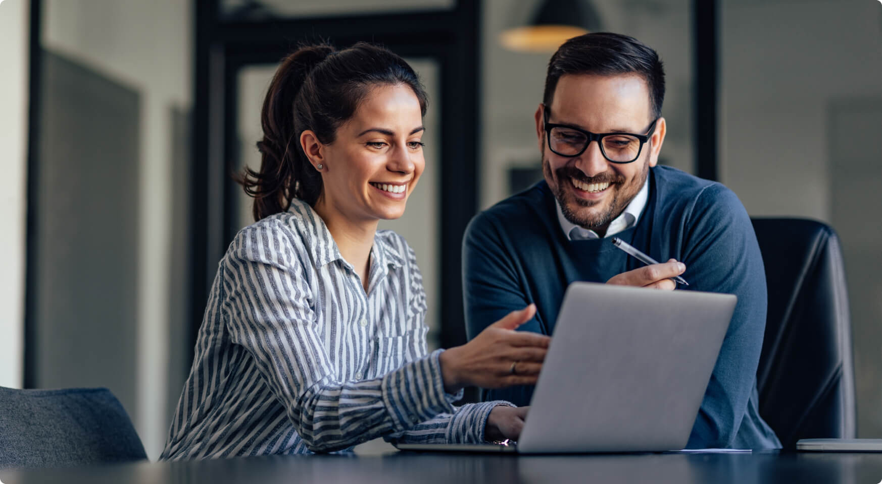 A financial advisor working with a client or team member in front of a laptop.