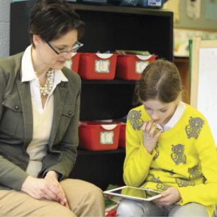 A TRPI associate helps a child learn about money management on her tablet.